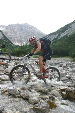 Mountainbiker beim berqueren eines Gebirgsbachs